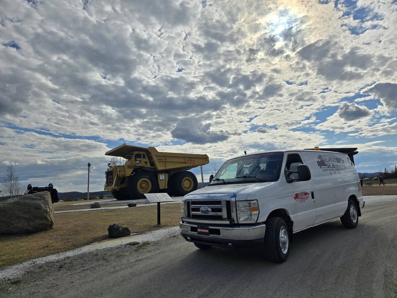 Fourgonnette de service devant un gros camion minier Cat 789 jaune